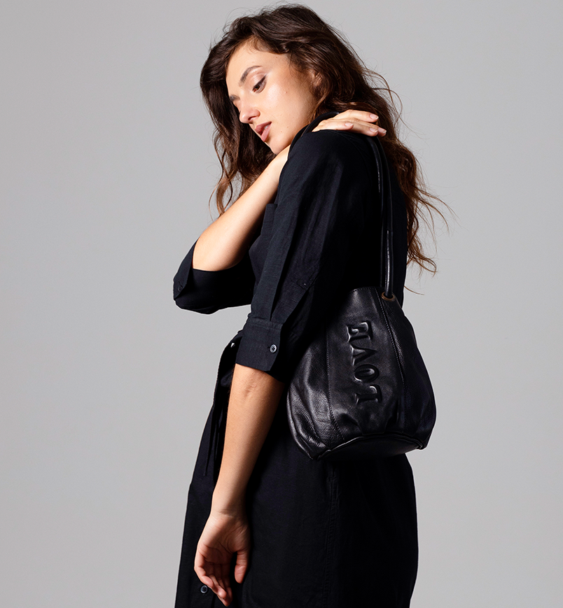 Woman wearing a black outfit with a black bag on a gray background