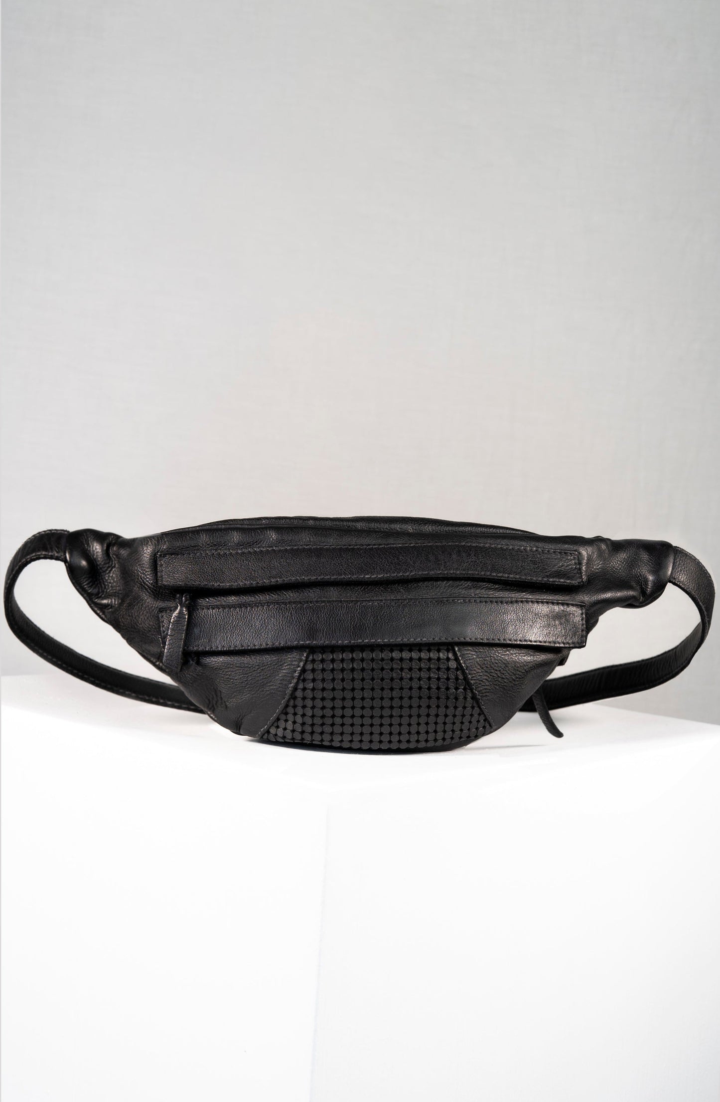 Black leather waist bag on a light gray background